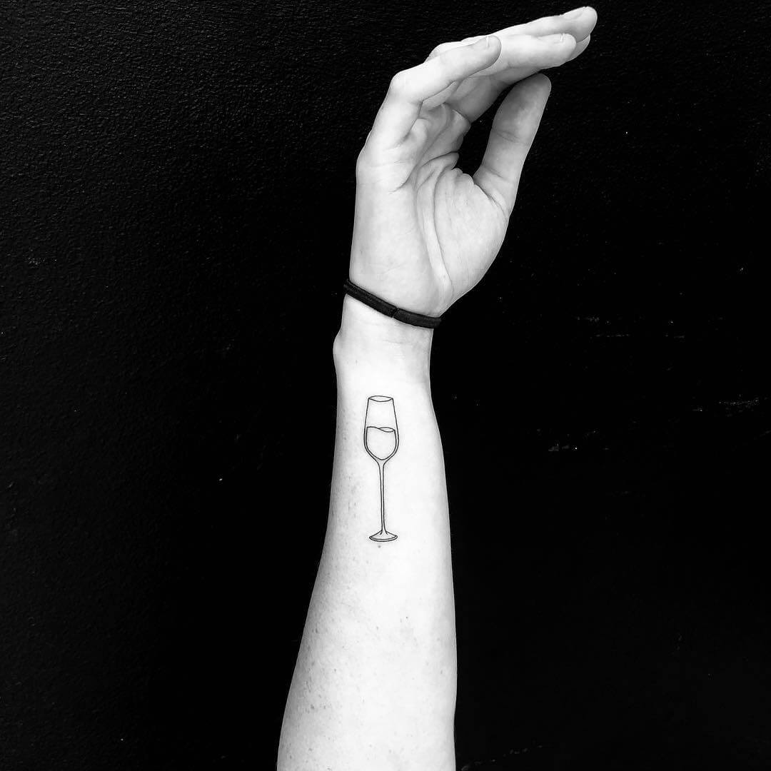 Glass of wine on arm minimal tattoo